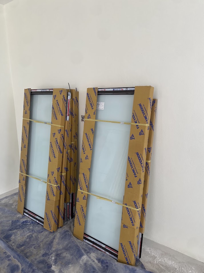 Cửa kính FANCYDOOR mới bọc carton dựng trong phòng đang thi công
